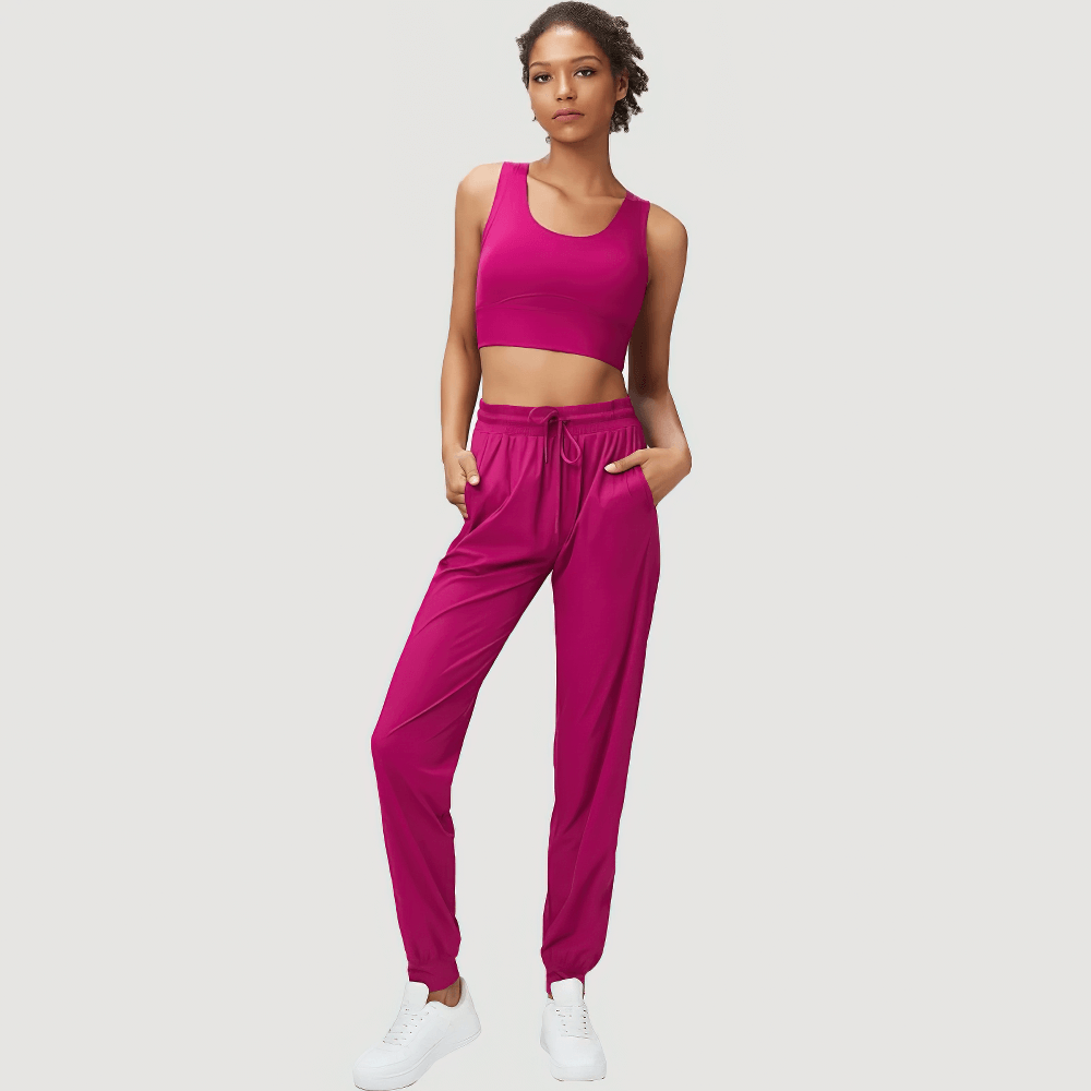 Woman wearing vibrant pink joggers and sports bra set, showcasing stylish fitness apparel with adjustable drawstrings for perfect fit.